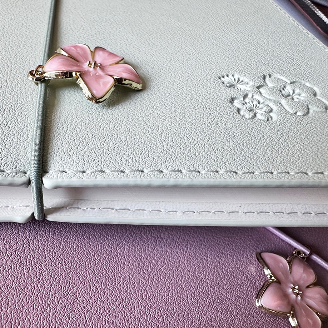 SAKURA journal for girls in stylish fashion colors, high-quality paper, compact and easy to carry, with elastic band and brass floral pendant. By Victoria's Journals.