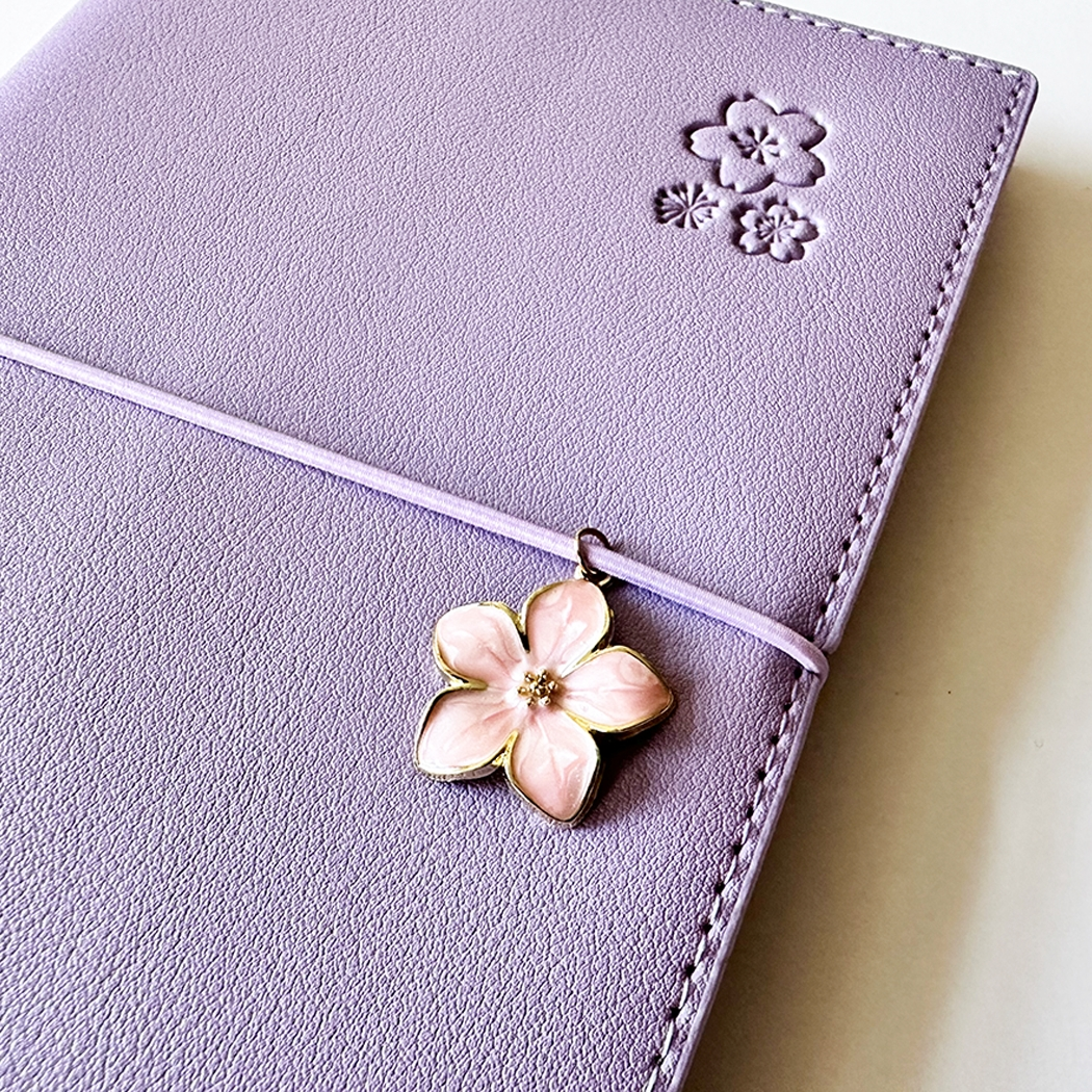 SAKURA journal for girls in stylish fashion colors, high-quality paper, compact and easy to carry, with elastic band and brass floral pendant. By Victoria's Journals. Lilac